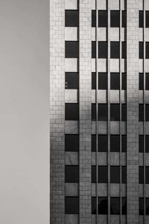 Black and white fragment of facade of tall multistory brick and concrete building