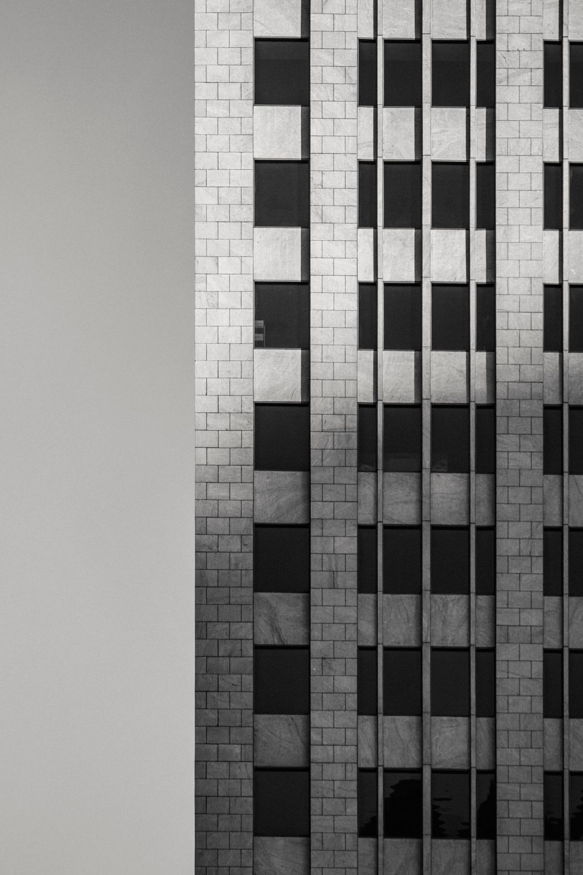 Black and white photo of a modern apartment facade with a geometric grid of windows.