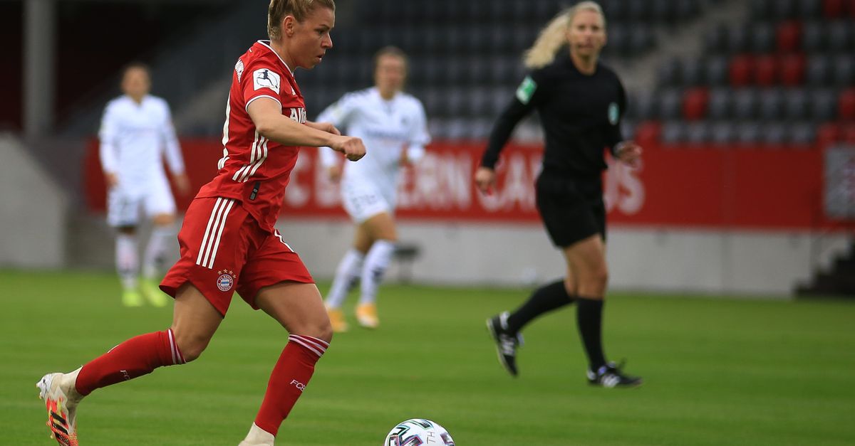 female soccer player doing a bicycle kick in a packed stadium