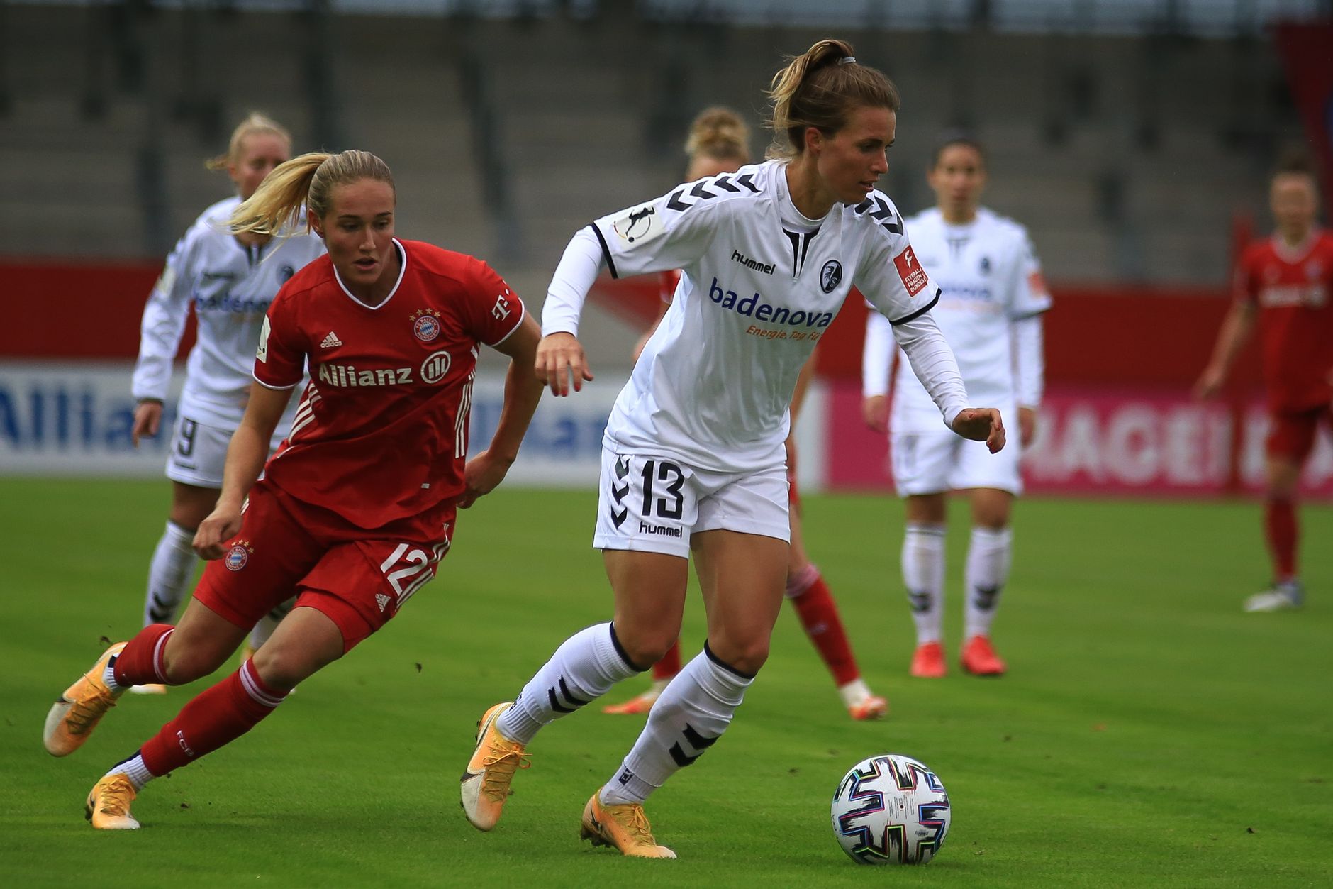 Action shot of women soccer players competing in an outdoor match, showcasing skill and determination.