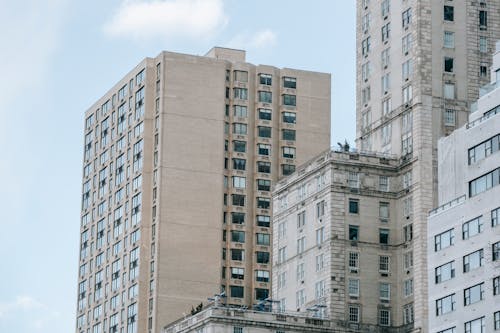 Low angle of tall multistory apartment buildings with balconies located in residential district against blue sky