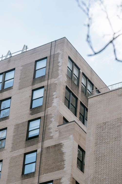 Free Low angle of old brick residential building with rectangular windows located in living zone Stock Photo