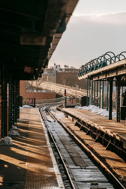 Stain rail tracks going between empty concrete platforms at station in winter day