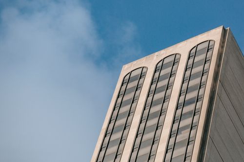 Free From below exterior of weathered multistory house with glass windows located on street against sky with white clouds in city Stock Photo