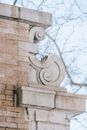Low angle of weathered stone cornice on column of old brick building against leafless branches