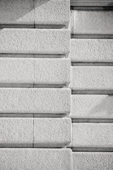 Close-up of a symmetrical textured concrete wall in black and white, emphasizing pattern and detail.