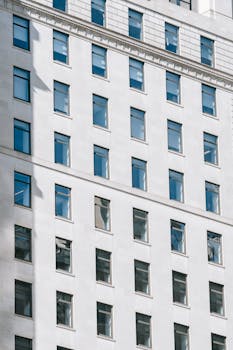From below of tall multistory apartment building with many windows and plaster cornice