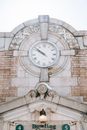 Low angle of round clock on old brick wall with decorative elements and lamp