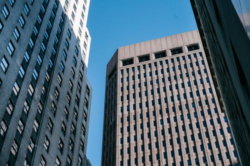 Free Low angle of multistory commercial and office buildings located in modern district against blue sky Stock Photo