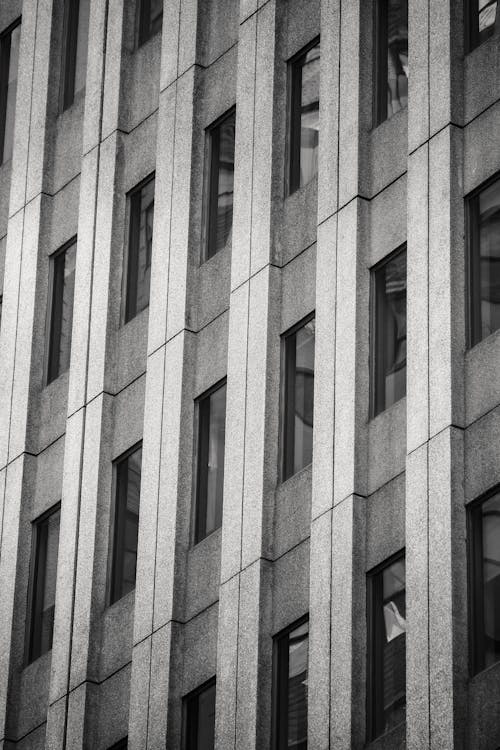 Black and white low angle full frame background of tall concrete walled building with narrow windows