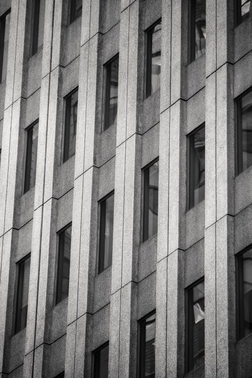 Free Black and white low angle full frame background of tall concrete walled building with narrow windows Stock Photo