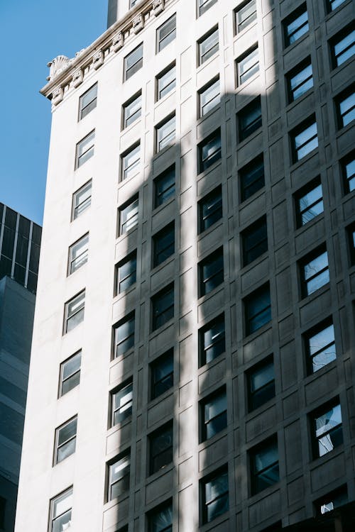 From below of multistory apartment building made of stone located in residential complex in city