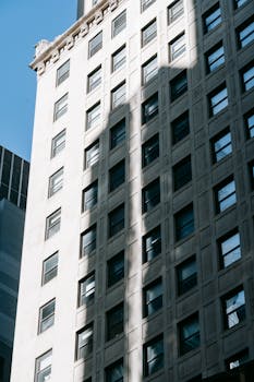 From below of multistory apartment building made of stone located in residential complex in city