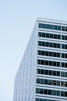 A contemporary glass skyscraper set against a clear blue sky, showcasing urban architecture.