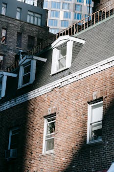 Cityscape with old brick building facade with windows and attic at roof in sunlight
