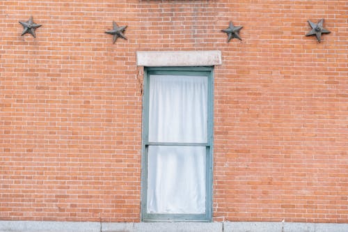Free Exterior of aged red brick building with curtained window and star shaped decoration Stock Photo
