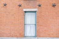 Exterior of aged red brick building with curtained window and star shaped decoration