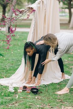 Two women performing yoga outdoors, focusing on guidance and relaxation in a peaceful park.