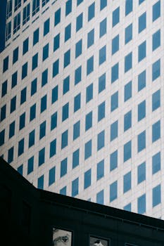 Low angle exterior design of contemporary urban high rise building with gray panels and geometric pattern of windows for architecture background
