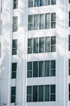 Closeup of a modern building facade with glass windows reflecting sunlight.