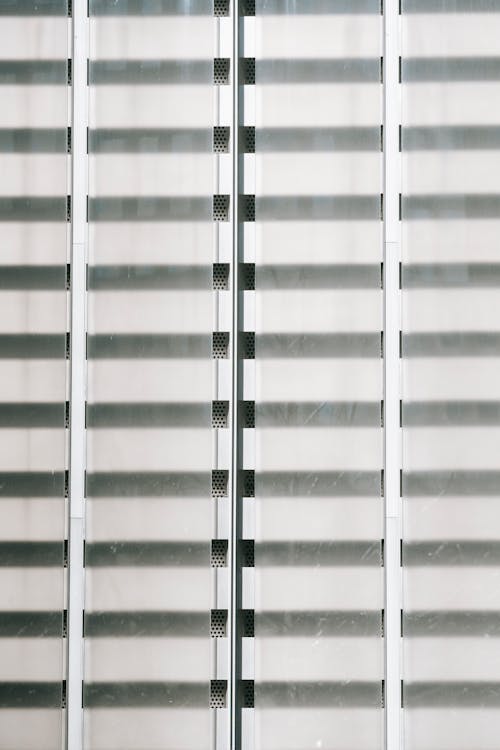 Geometric architecture background of exterior of transparent glass window closed with shutter stripes