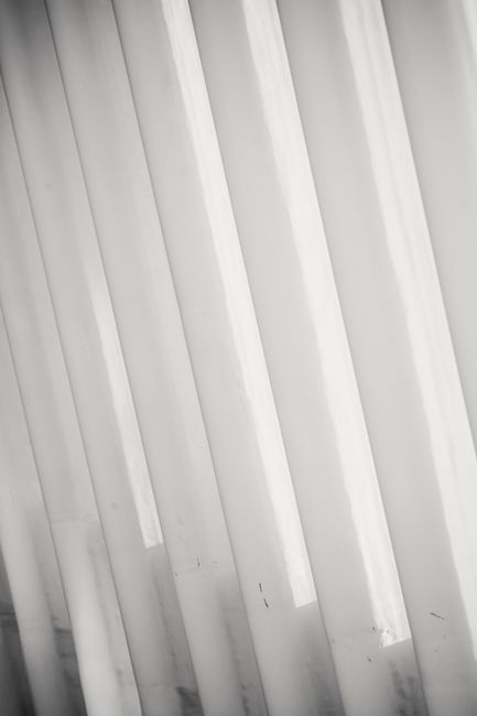 Minimalist style geometric textured background of white vertical shutters on window with sunlight