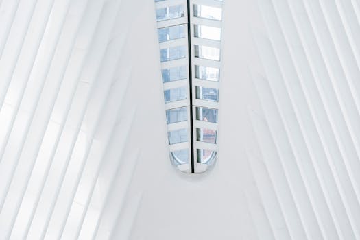 From below of geometric white walls of contemporary building with glass windows on ceiling in terminal station on sunny day in New York