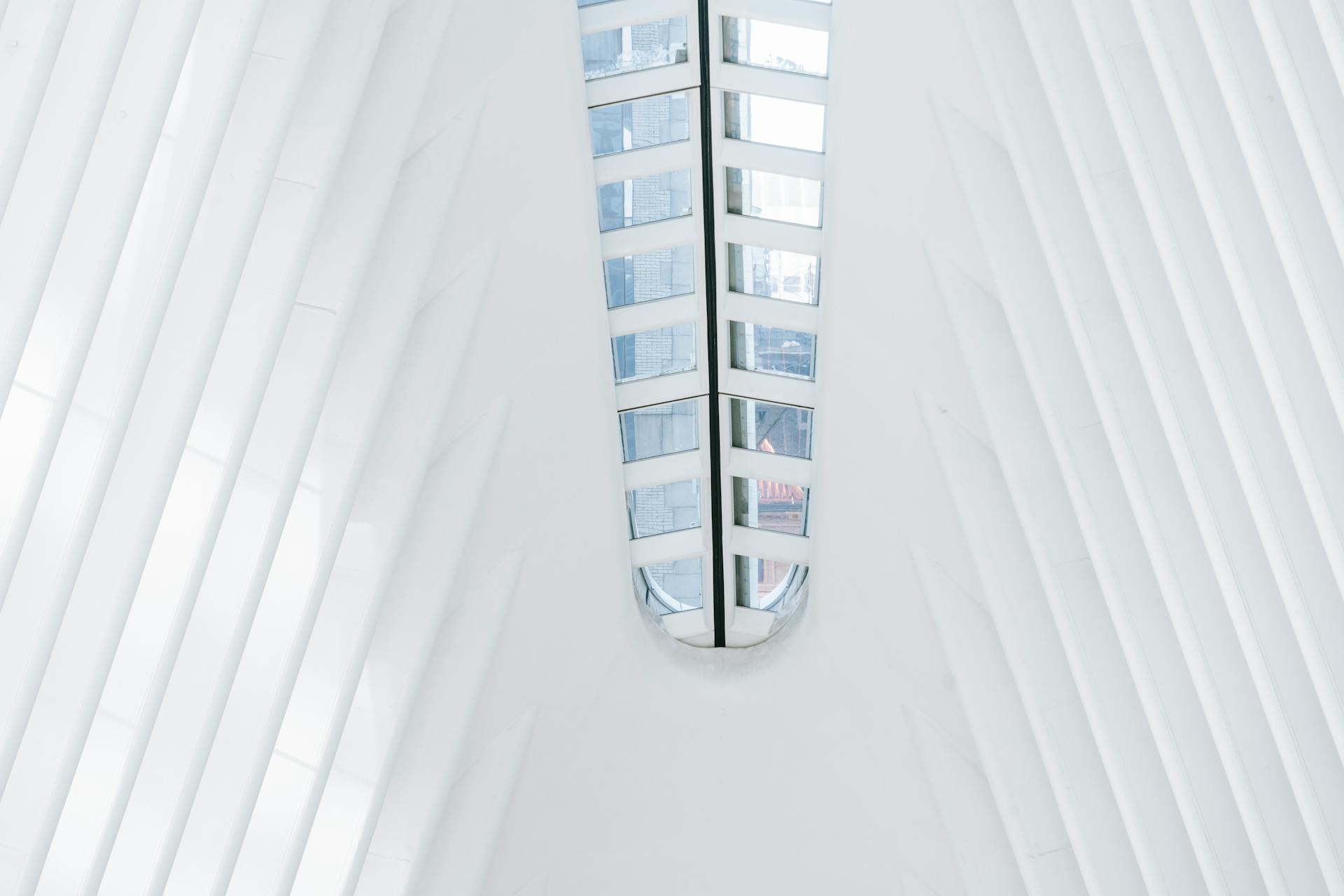 From below of geometric white walls of contemporary building with glass windows on ceiling in terminal station on sunny day in New York