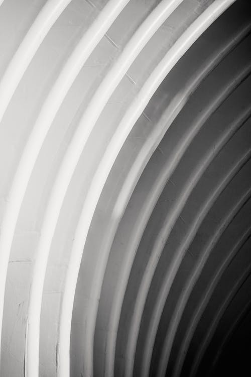 From below of textured white arched wall of modern minimalist building in daylight