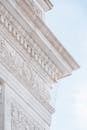 From below of bas reliefs and carved ornaments on marble facade of historical Washington Square Arch under cloudy blue sky in New York