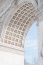 From below of ornamental ceiling of historic Washington Square Arch against cloudy blue sky in New York