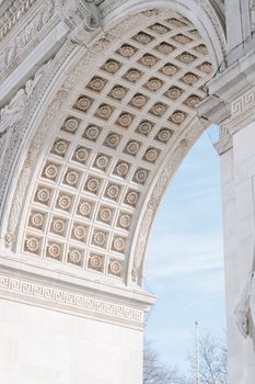 From below of ornamental ceiling of historic Washington Square Arch against cloudy blue sky in New York