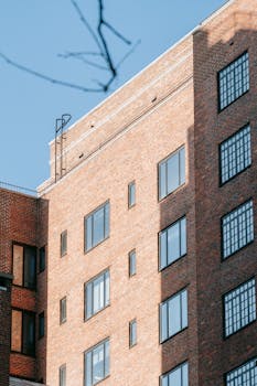 Low angle view of a modern brick building with clear blue sky, showcasing urban architecture.
