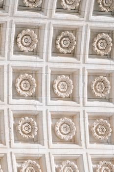 From below of carved marble floral ornaments decorating ceiling of historic triumphal arch located in Washington Square Park on sunny day in New York