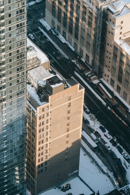 Free From above of multistory buildings and skyscraper with glass facade in snowy New York City district on sunny winter day Stock Photo