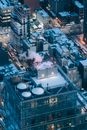 Aerial view of vehicles driving on asphalt roads between residential multistory buildings with lights in windows