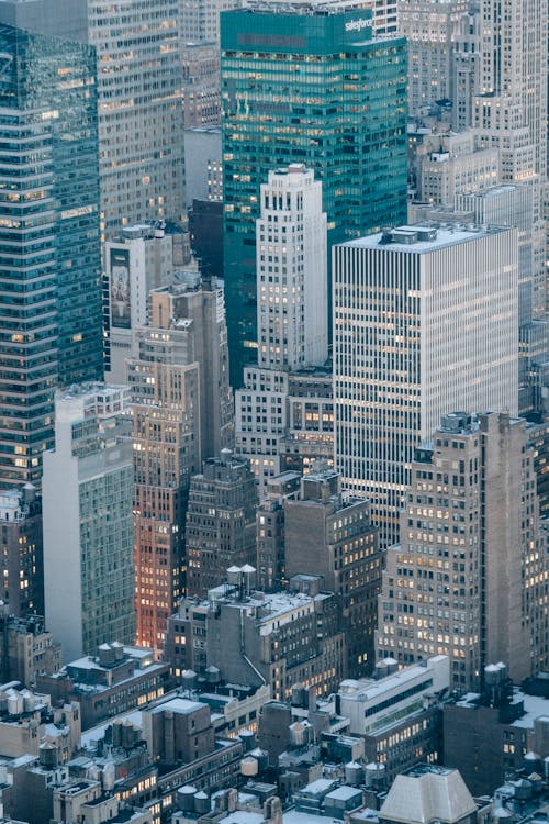 Drone view of multistory residential buildings and commerce skyscrapers with lights in windows located in modern city district