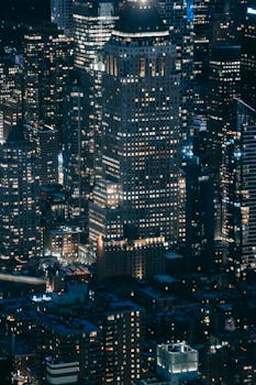 Stunning aerial view of a brightly illuminated cityscape featuring modern skyscrapers at night.
