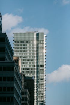 Exterior of modern multistory buildings and skyscraper with windows under cloudy blue sky in daylight in town district