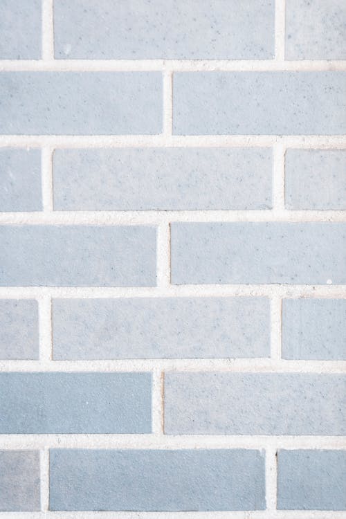 Full frame minimalist background of light gray wall with rows of bricks on wall