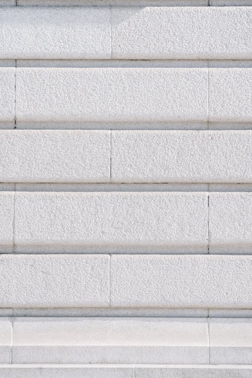 Full frame textured background of white wall with rows of bricks at daylight