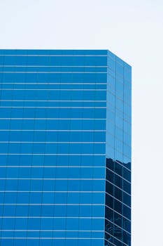 Low angle view of a contemporary glass skyscraper reflecting the clear sky.