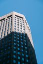 From below of high office tower located in central district of megapolis under blue cloudless sky