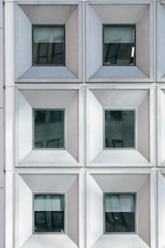 Symmetrical facade of a modern building with glass windows and white geometric frame.
