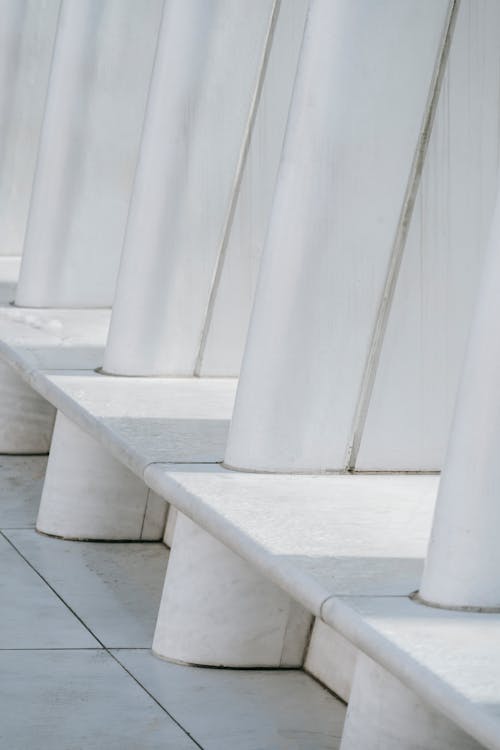 Row white concrete columns for supporting roof on tiled floor in building made in minimalist style