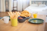 A cozy breakfast setup featuring croissants, orange juice, and breadsticks on a wooden table indoors.