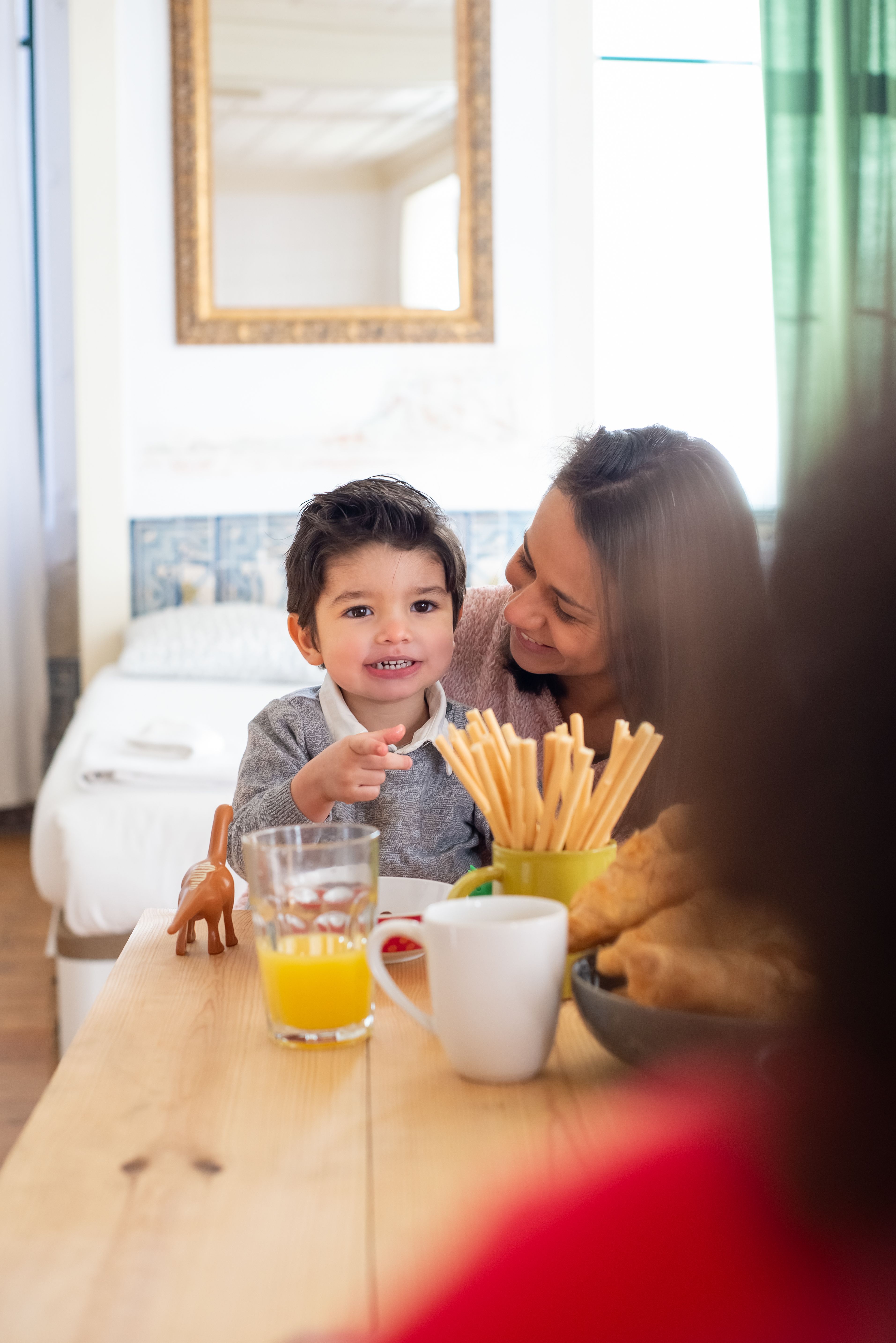 An adult smiling with a young child at a breakfast table