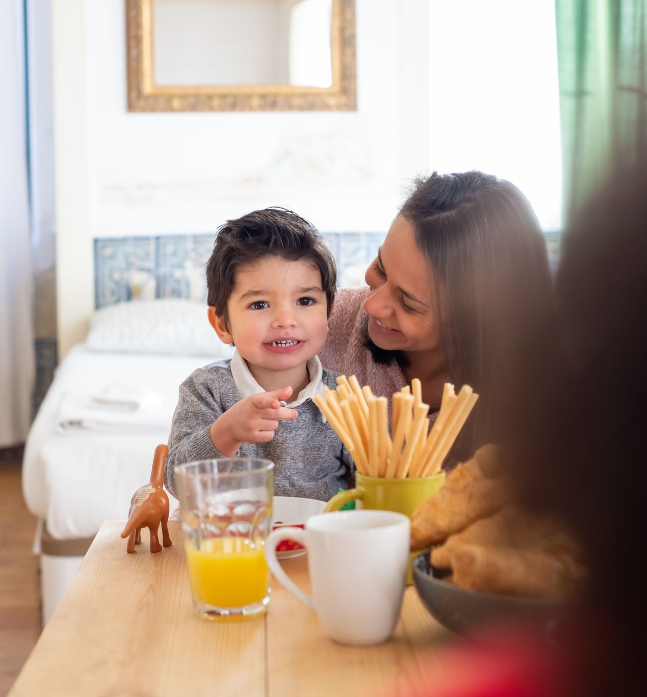 An adult smiling with a young child at a breakfast table