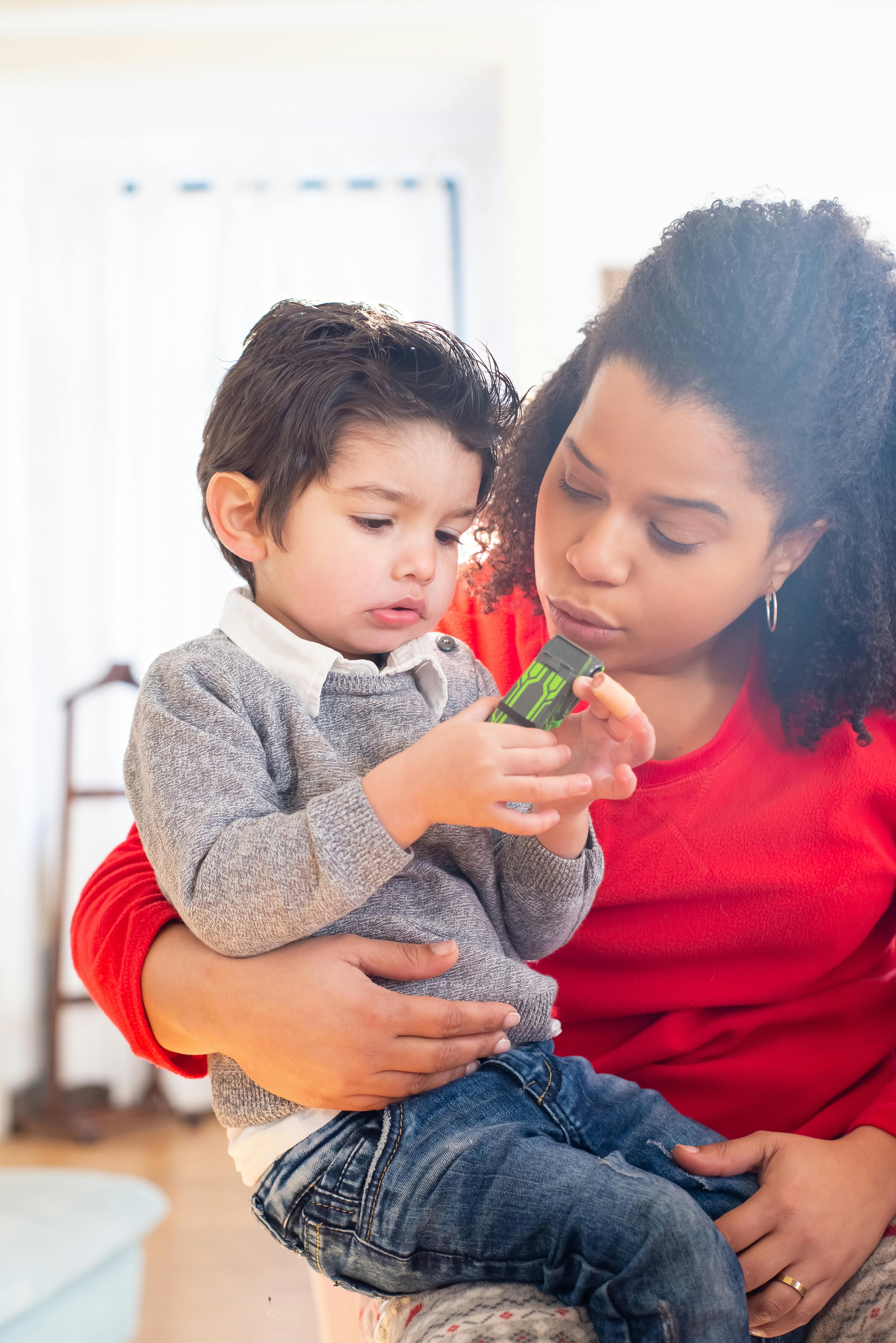 a child holding a toy while sitting on his mother s lap