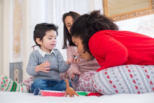 Free Curly Haired Woman in Red Long Sleeves Playing with the Boy  Stock Photo